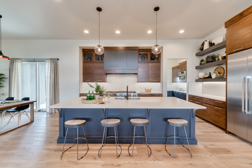 This is an example of a mid-sized contemporary l-shaped open plan kitchen in Boise with flat-panel cabinets, medium wood cabinets, quartz benchtops, white splashback, glass tile splashback, stainless steel appliances, light hardwood floors, with island, an undermount sink, beige floor and white benchtop.