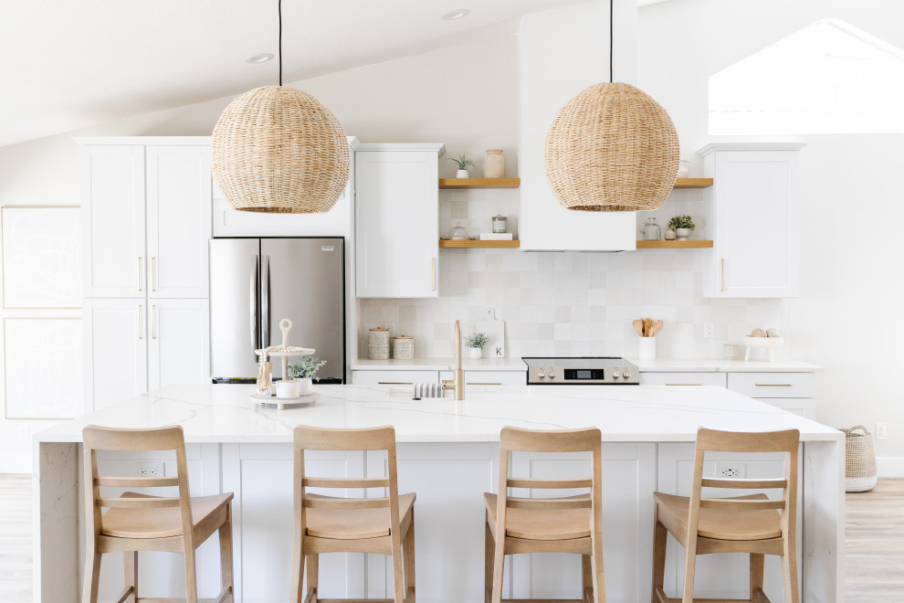 Small beach style single-wall open plan kitchen in Phoenix with a single-bowl sink, shaker cabinets, white cabinets, quartz benchtops, white splashback, porcelain splashback, stainless steel appliances, vinyl floors, with island, brown floor, white benchtop and vaulted.