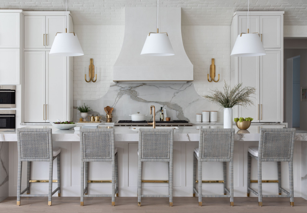 Open concept kitchen - huge transitional single-wall medium tone wood floor, brown floor and vaulted ceiling open concept kitchen idea in Houston with a farmhouse sink, recessed-panel cabinets, white cabinets, marble countertops, gray backsplash, marble backsplash, stainless steel appliances, an island and gray countertops