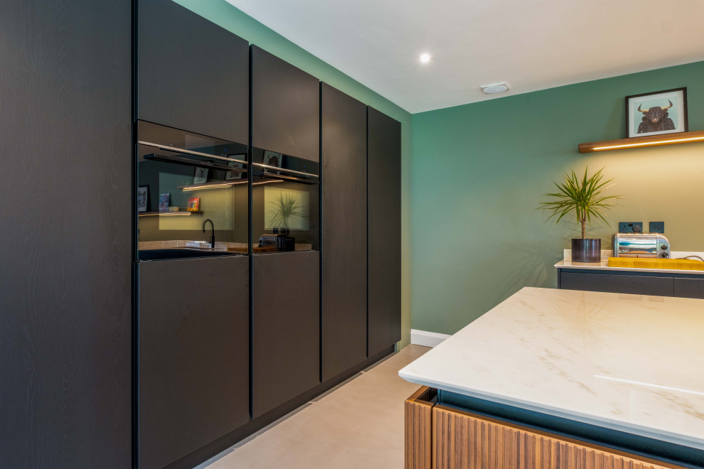 This is an example of a modern kitchen in Sussex with an island and grey floors.