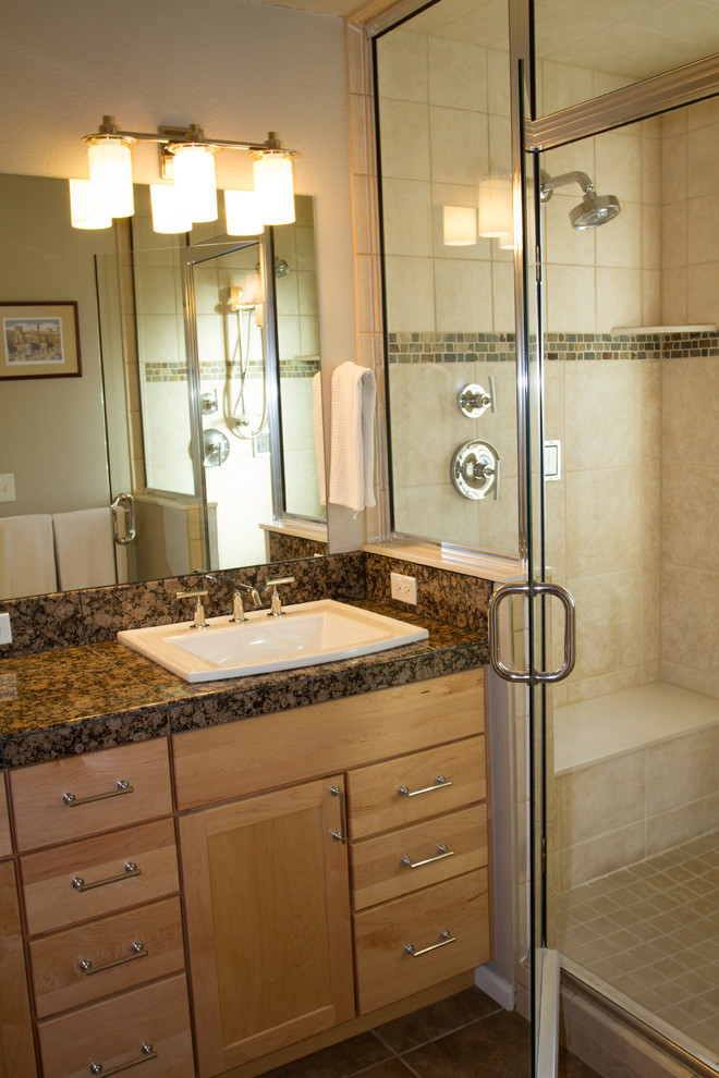 This is an example of a small traditional bathroom in Denver with a drop-in sink, a two-piece toilet, recessed-panel cabinets, light wood cabinets, granite benchtops, gray tile, porcelain tile, porcelain floors, beige walls, with a sauna, an alcove shower, brown floor and a hinged shower door.