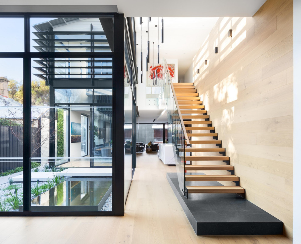 Design ideas for a contemporary wood floating staircase in Melbourne with open risers and glass railing.