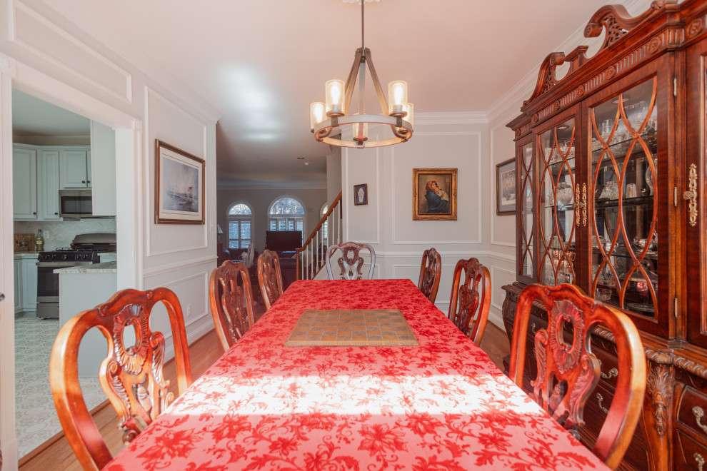 Foto di una grande sala da pranzo aperta verso il soggiorno classica con pareti grigie, parquet scuro, pavimento marrone e pareti in legno