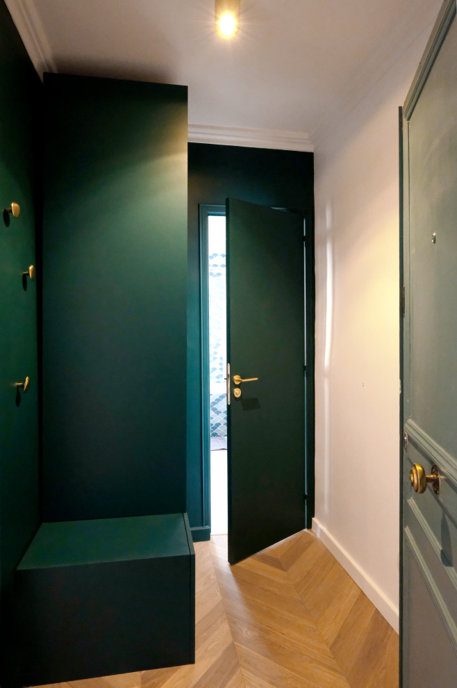 Foto på en liten funkis hall, med gröna väggar, ljust trägolv och beiget golv