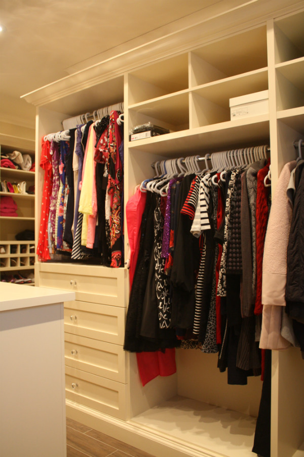 This is an example of a large transitional women's walk-in wardrobe in Other with glass-front cabinets, white cabinets and ceramic floors.