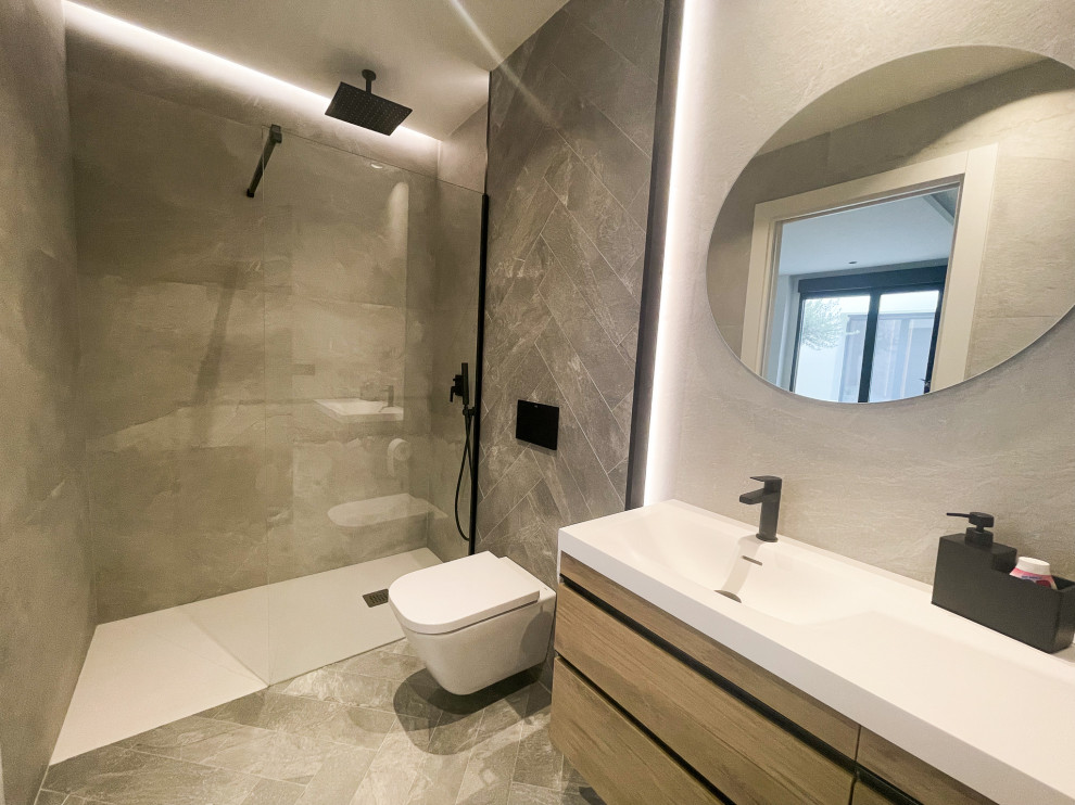 Photo of a large modern master bathroom in Valencia with marble, laminate floors, a wall-mount sink, quartzite benchtops, grey floor, a single vanity, a floating vanity, brown cabinets, a curbless shower, gray tile, grey walls and white benchtops.
