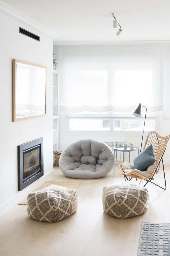 Идея дизайна: большая открытая гостиная комната в скандинавском стиле с белыми стенами, светлым паркетным полом, стандартным камином, фасадом камина из штукатурки, отдельно стоящим телевизором, коричневым полом и ковром на полу
