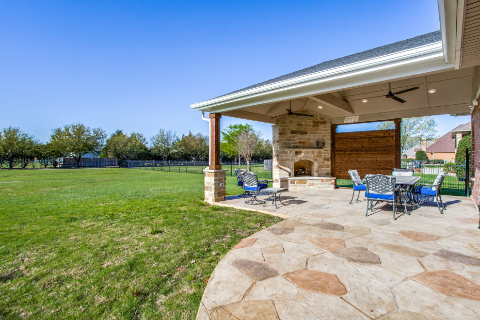 Große, Überdachte Eklektische Veranda hinter dem Haus mit Kamin und Stempelbeton in Dallas