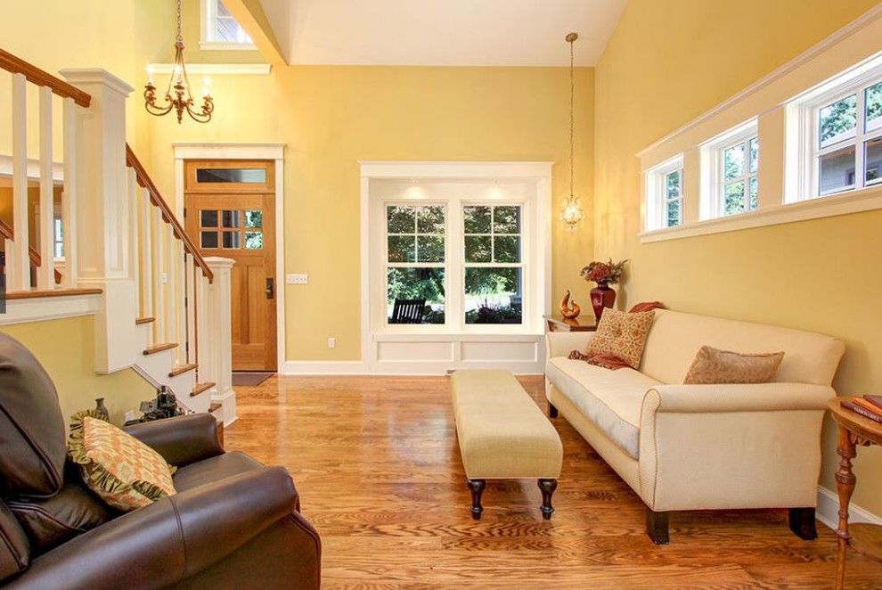 This is an example of a mid-sized traditional open concept living room in Seattle with yellow walls, medium hardwood floors, no fireplace and no tv.