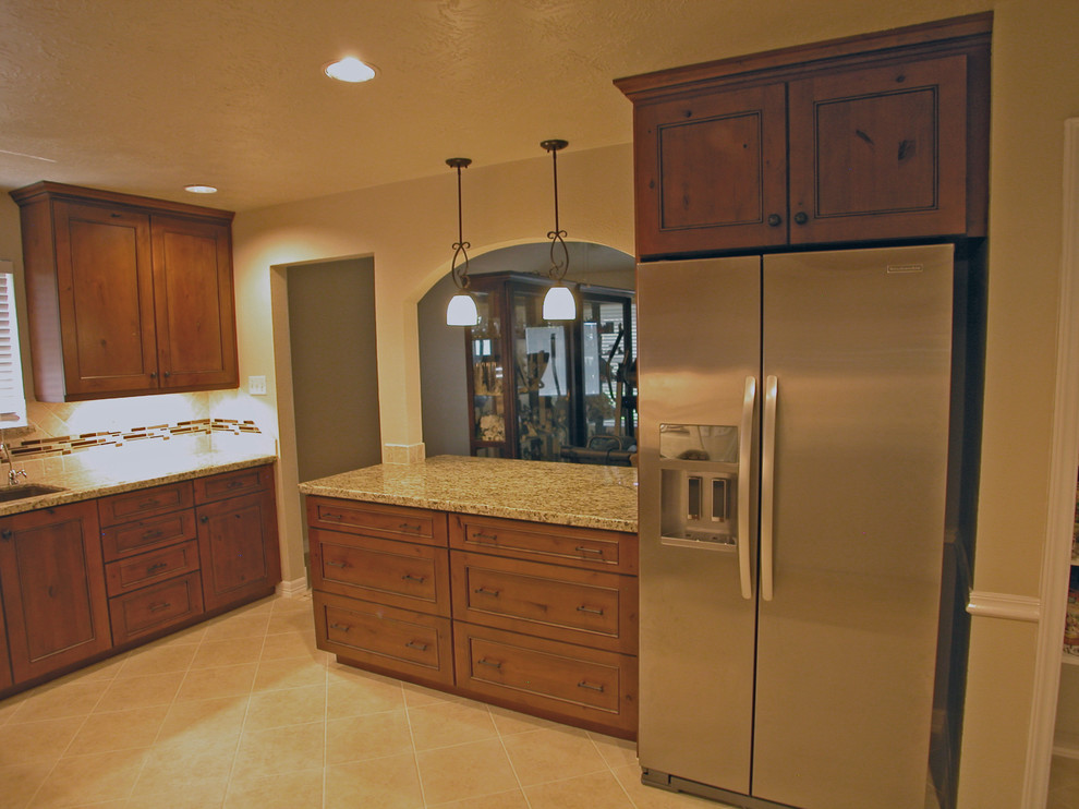 Mid-sized country l-shaped eat-in kitchen in Houston with an undermount sink, recessed-panel cabinets, brown cabinets, granite benchtops, beige splashback, glass tile splashback, stainless steel appliances, ceramic floors and no island.