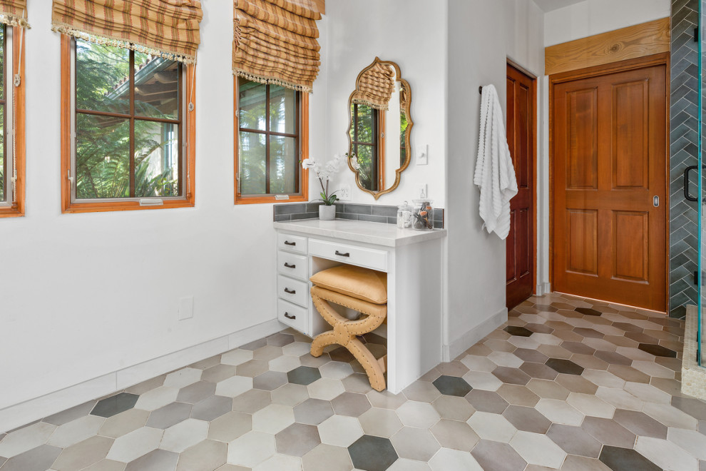 Photo of a large mediterranean master bathroom in San Diego with shaker cabinets, white cabinets, a freestanding tub, an alcove shower, green tile, ceramic tile, white walls, ceramic floors, an undermount sink, grey floor, a hinged shower door, beige benchtops, a niche, a double vanity and a built-in vanity.