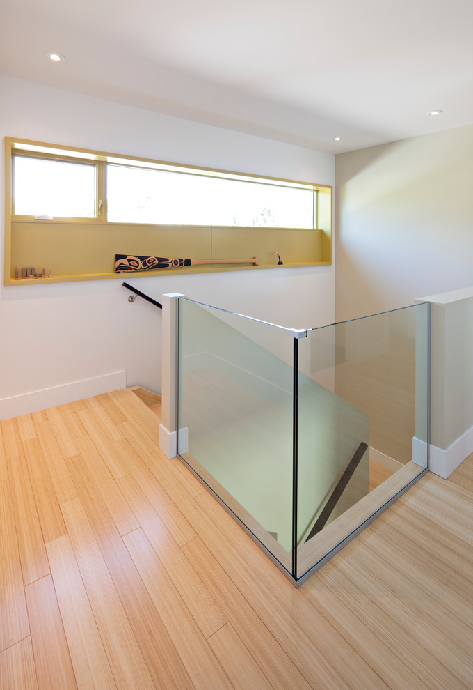 Mid-sized contemporary wood straight staircase in Calgary with wood risers and glass railing.