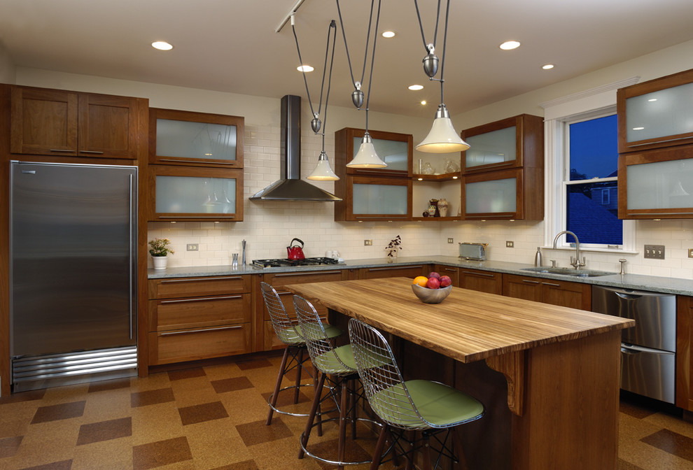 Photo of a contemporary l-shaped kitchen in Chicago with stainless steel appliances, shaker cabinets, dark wood cabinets, wood benchtops, white splashback and subway tile splashback.
