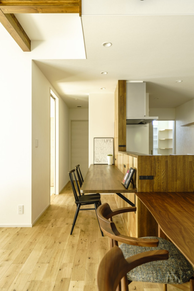 This is an example of a mid-sized modern single-wall open plan kitchen in Other with beaded inset cabinets, brown cabinets, solid surface benchtops, white splashback, light hardwood floors, brown floor, brown benchtop and wallpaper.