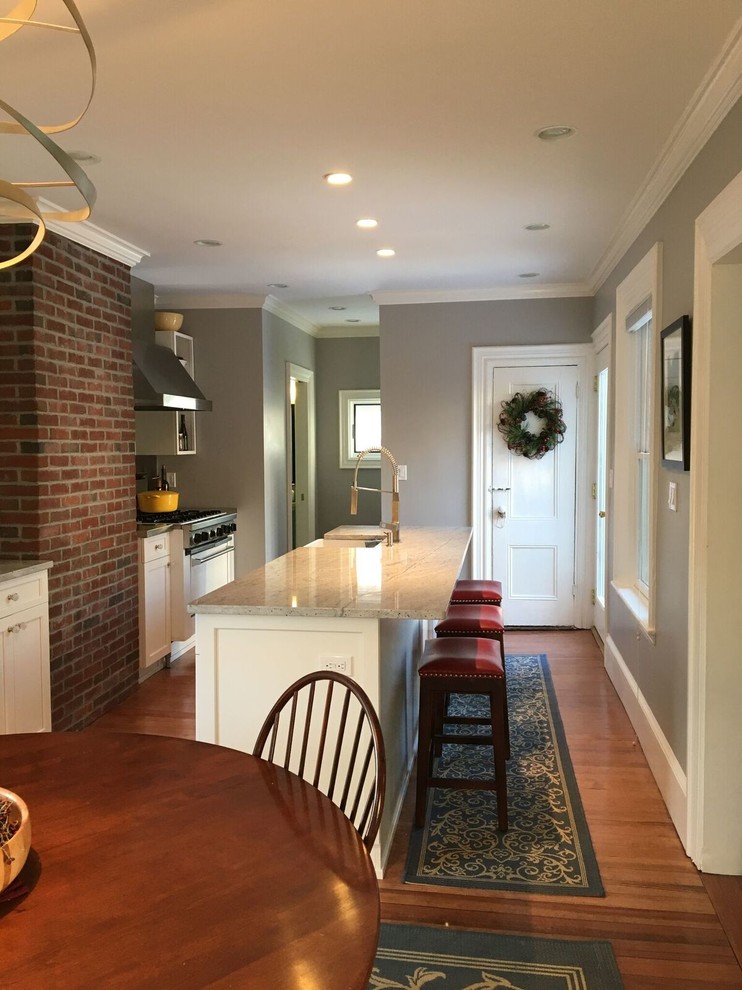 Inspiration for a large transitional l-shaped light wood floor eat-in kitchen remodel in Boston with a drop-in sink, shaker cabinets, white cabinets, marble countertops, gray backsplash, stainless steel appliances and an island