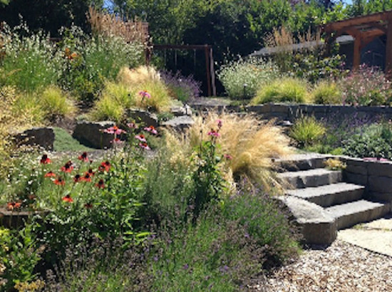 Inspiration for a mid-sized backyard full sun garden in Portland with a retaining wall and natural stone pavers.