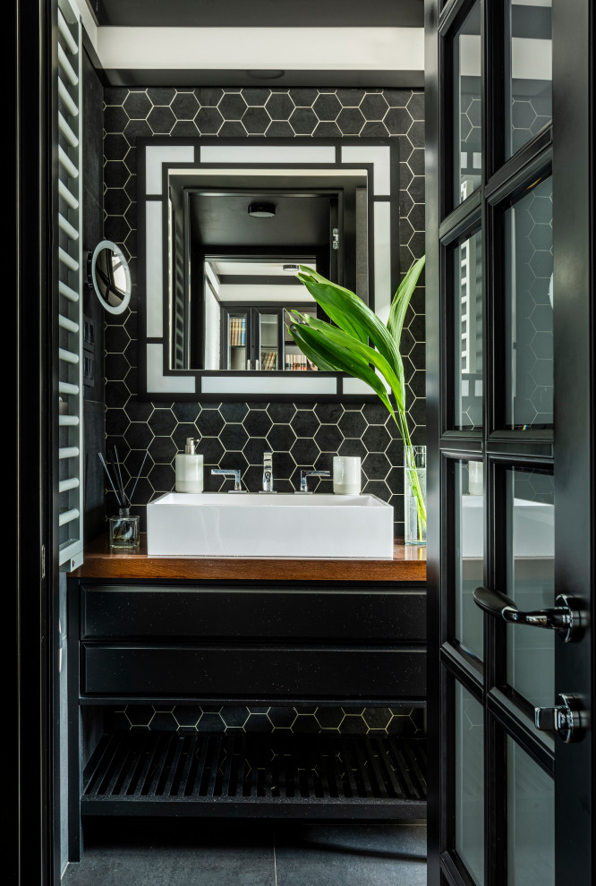 Идея дизайна: маленькая серо-белая ванная комната в стиле неоклассика (современная классика) с фасадами с выступающей филенкой, черными фасадами, душем в нише, инсталляцией, черно-белой плиткой, керамической плиткой, полом из керамической плитки, душевой кабиной, накладной раковиной, столешницей из дерева, черным полом, душем с распашными дверями, коричневой столешницей, гигиеническим душем, тумбой под одну раковину и встроенной тумбой для на участке и в саду