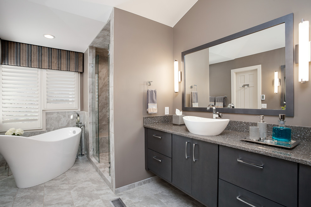Inspiration for a mid-sized transitional master bathroom in Denver with a vessel sink, flat-panel cabinets, dark wood cabinets, quartzite benchtops, a freestanding tub, a curbless shower, a one-piece toilet, beige tile, porcelain tile, grey walls and porcelain floors.