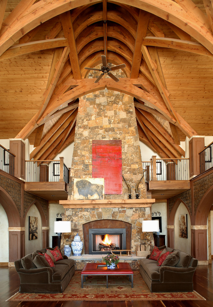 This is an example of a country open concept living room in Denver with beige walls, dark hardwood floors, a standard fireplace and a stone fireplace surround.