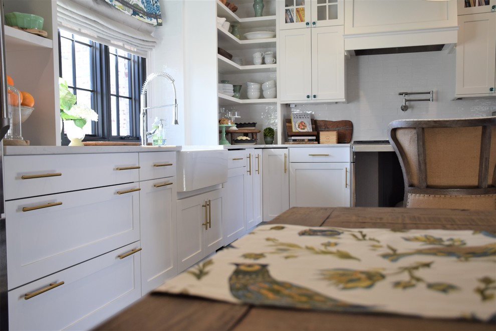 Example of a large transitional dark wood floor eat-in kitchen design with a farmhouse sink, shaker cabinets, white cabinets, quartzite countertops, white backsplash, subway tile backsplash, stainless steel appliances and an island