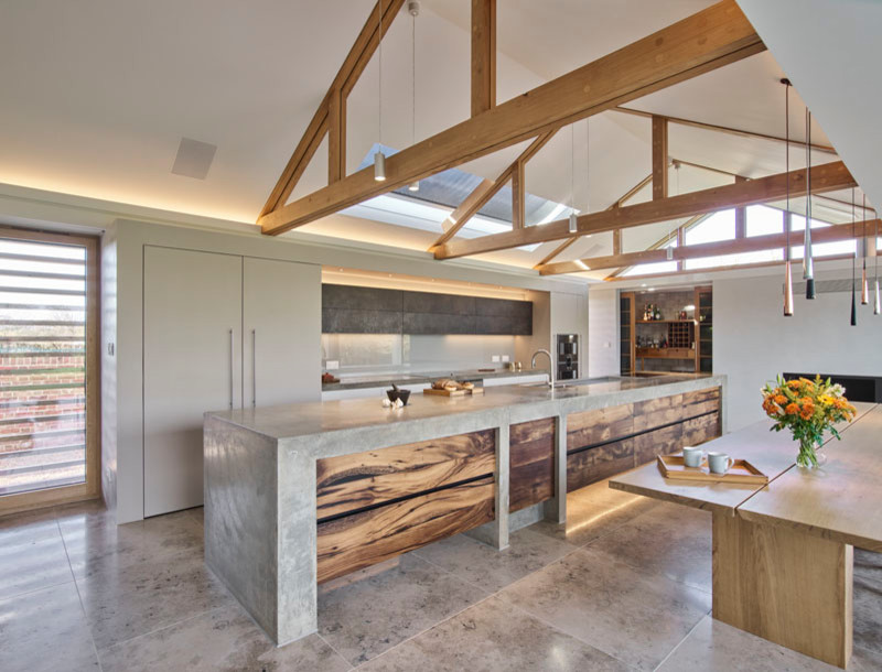 Expansive contemporary l-shaped eat-in kitchen in Cambridgeshire with an integrated sink, flat-panel cabinets, grey cabinets, concrete benchtops, grey splashback, glass sheet splashback, stainless steel appliances, porcelain floors, with island, multi-coloured floor and grey benchtop.