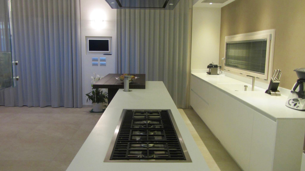 Inspiration for a large modern galley open plan kitchen in Bologna with an integrated sink, flat-panel cabinets, white cabinets, solid surface benchtops, stainless steel appliances, concrete floors, with island, beige floor and white benchtop.
