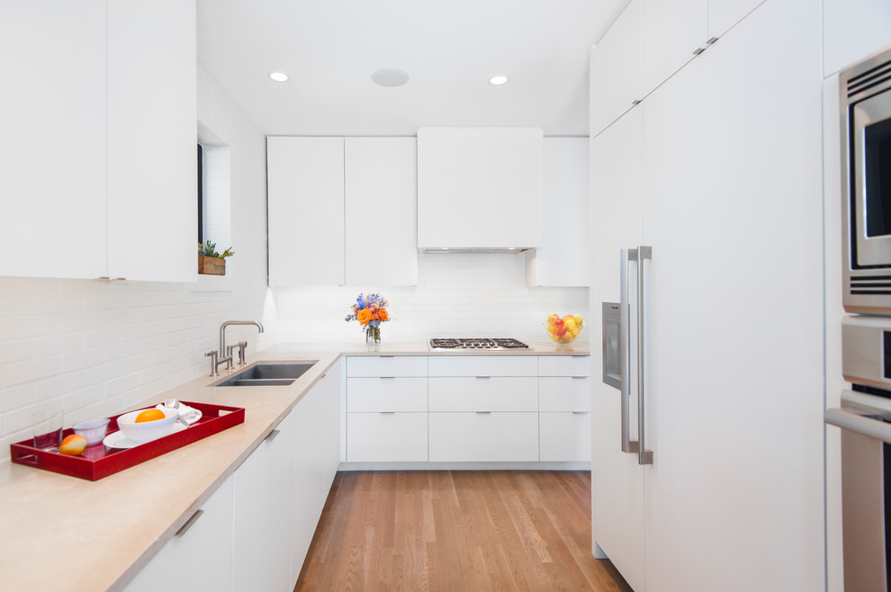 This is an example of a contemporary l-shaped kitchen in Austin with a double-bowl sink, flat-panel cabinets, white cabinets, white splashback, panelled appliances, medium hardwood floors and no island.