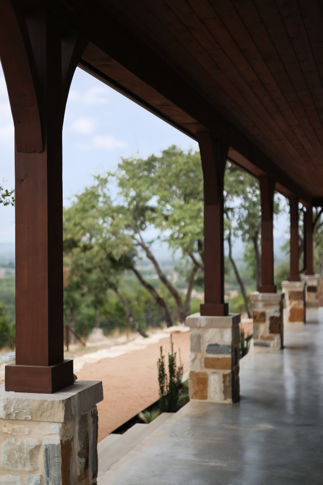 Country concrete back porch idea in Austin with a roof extension