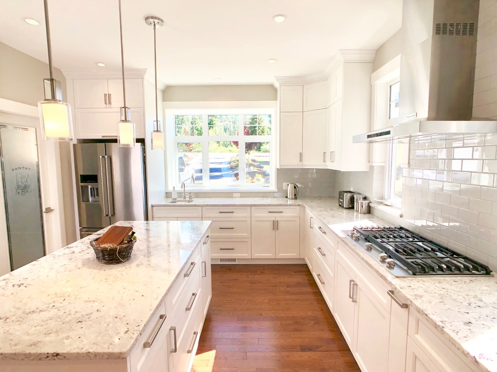Inspiration for a large transitional u-shaped open plan kitchen in Other with an undermount sink, shaker cabinets, white cabinets, quartz benchtops, white splashback, subway tile splashback, stainless steel appliances, light hardwood floors, with island, brown floor and white benchtop.