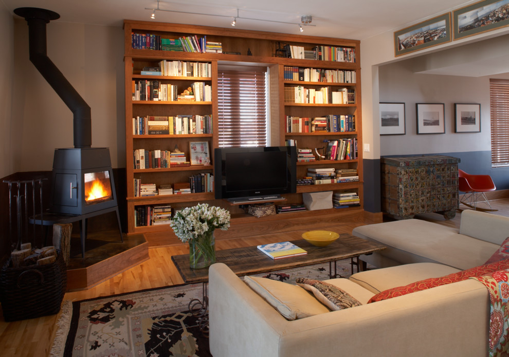 Inspiration for a mid-sized eclectic open concept family room in Minneapolis with a library, multi-coloured walls, light hardwood floors, no fireplace and a built-in media wall.