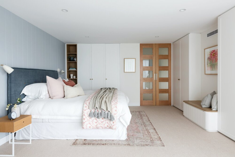 This is an example of a large beach style master bedroom in Sydney with blue walls, carpet, no fireplace, beige floor and planked wall panelling.