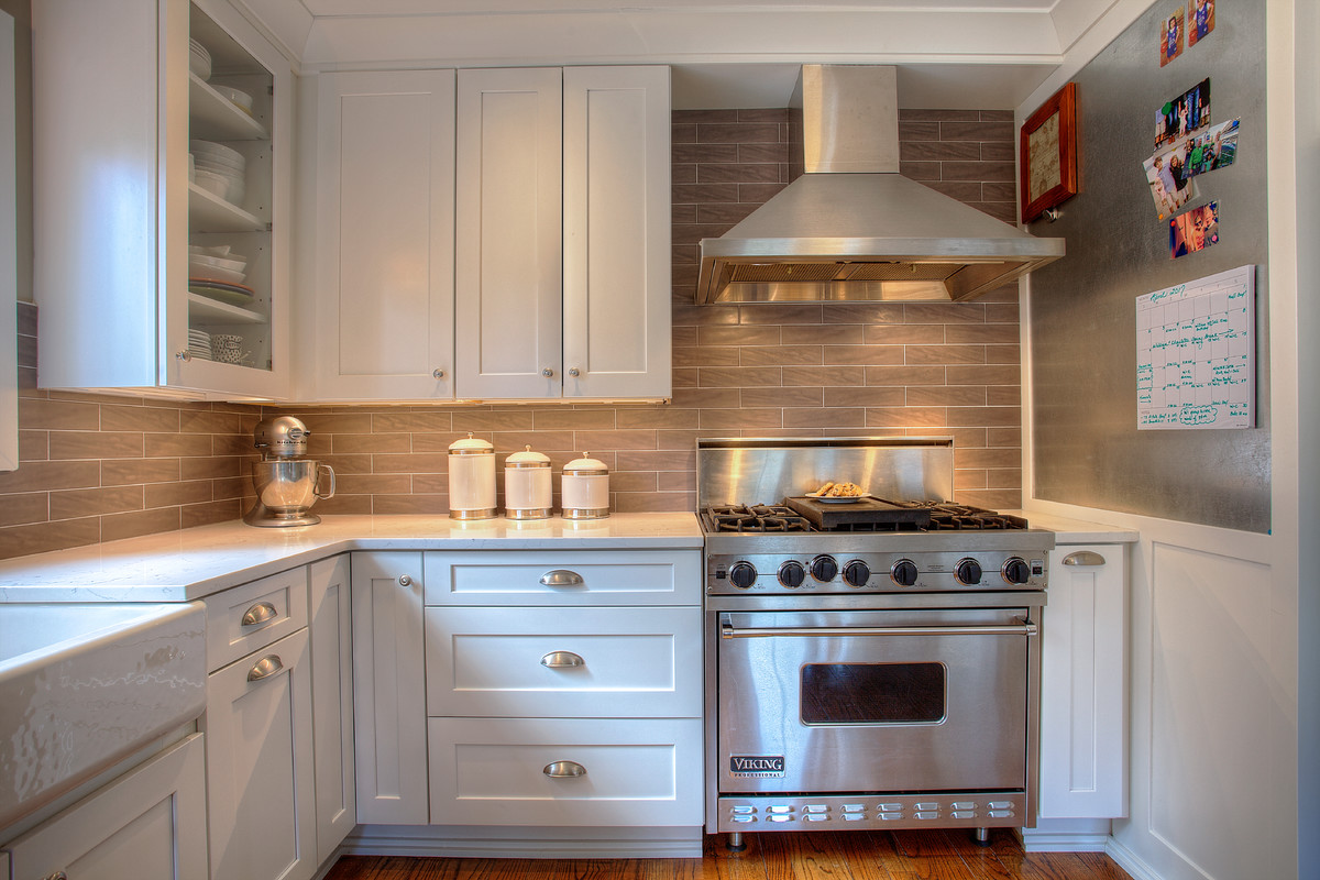 Inspiration for a mid-sized arts and crafts l-shaped separate kitchen in Seattle with a farmhouse sink, shaker cabinets, white cabinets, quartz benchtops, grey splashback, ceramic splashback, stainless steel appliances, medium hardwood floors and no island.