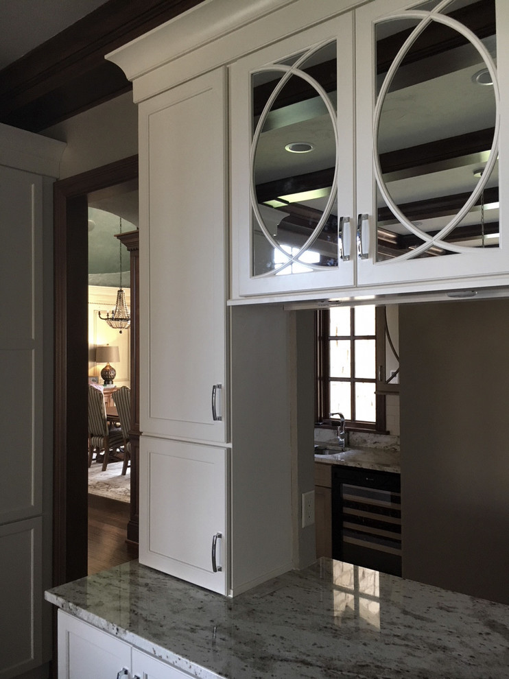 Eat-in kitchen - large transitional l-shaped dark wood floor and brown floor eat-in kitchen idea with a farmhouse sink, recessed-panel cabinets, white cabinets, granite countertops, white backsplash, ceramic backsplash, stainless steel appliances and an island