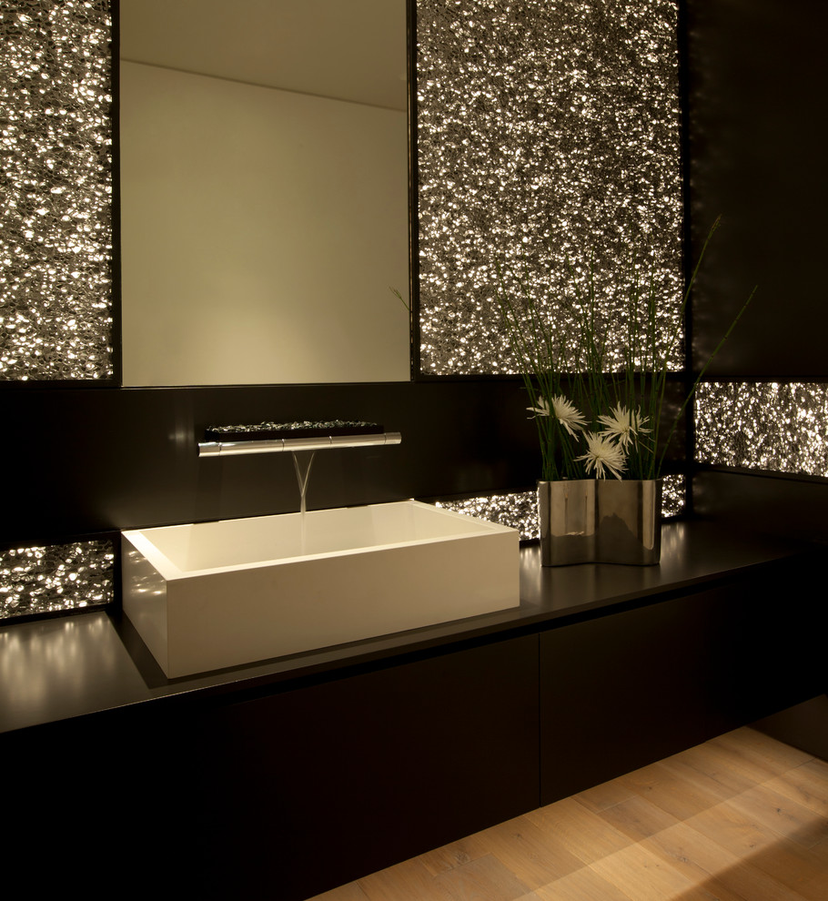 This is an example of a contemporary powder room in Orange County with a vessel sink, black tile and black benchtops.