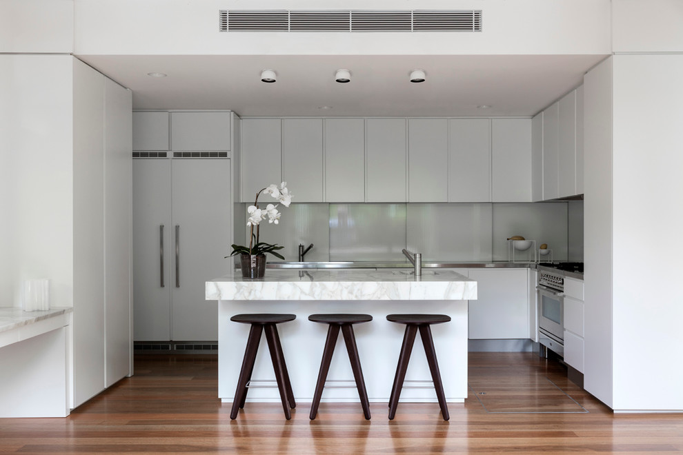 Inspiration for a large modern u-shaped eat-in kitchen in Sydney with an undermount sink, white cabinets, marble benchtops, glass sheet splashback, stainless steel appliances, light hardwood floors, white splashback and with island.