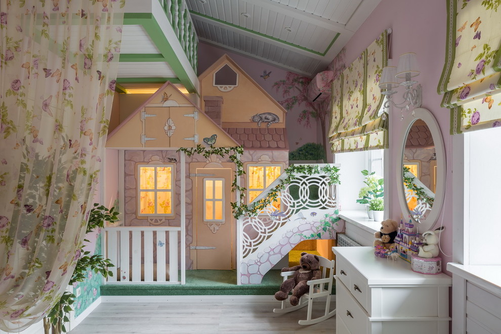This is an example of a transitional kids' playroom for girls in Other with pink walls and light hardwood floors.