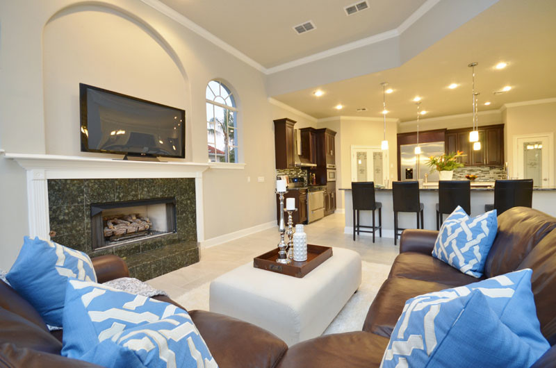This is an example of a contemporary living room in Orlando with beige walls, a standard fireplace, a stone fireplace surround and a wall-mounted tv.