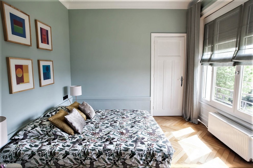 Mid-sized transitional guest bedroom in Lyon with green walls, light hardwood floors, a standard fireplace, a stone fireplace surround and beige floor.
