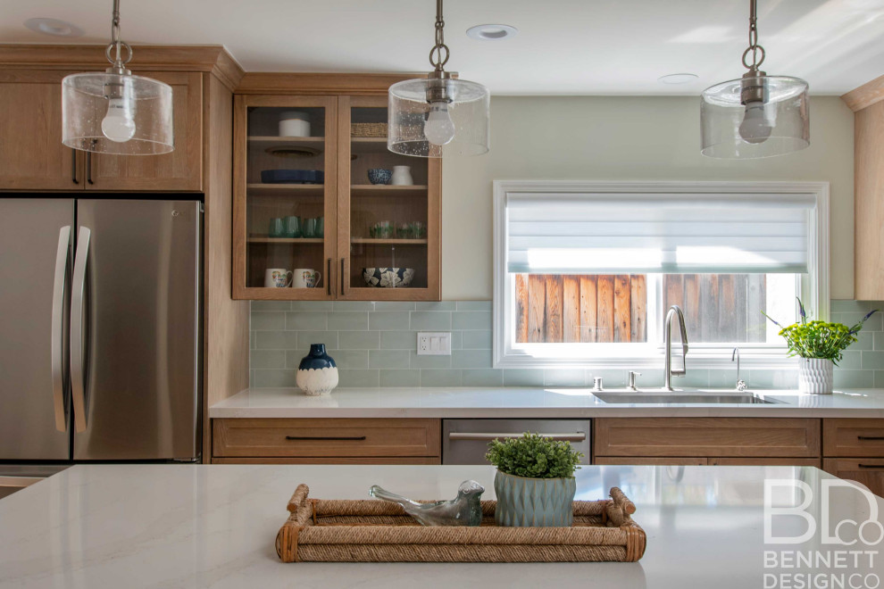 Inspiration for a mid-sized beach style l-shaped open plan kitchen in San Francisco with an undermount sink, shaker cabinets, medium wood cabinets, quartz benchtops, blue splashback, ceramic splashback, stainless steel appliances, light hardwood floors, with island, blue floor and white benchtop.