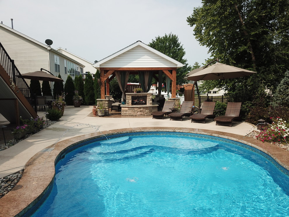 Inspiration for a mid-sized contemporary backyard custom-shaped pool in St Louis with a water feature and stamped concrete.