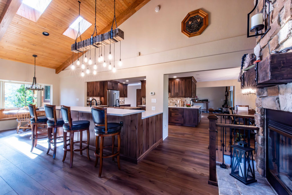 Inspiration for a large country open plan dining in Denver with beige walls, dark hardwood floors, a standard fireplace, brown floor and vaulted.
