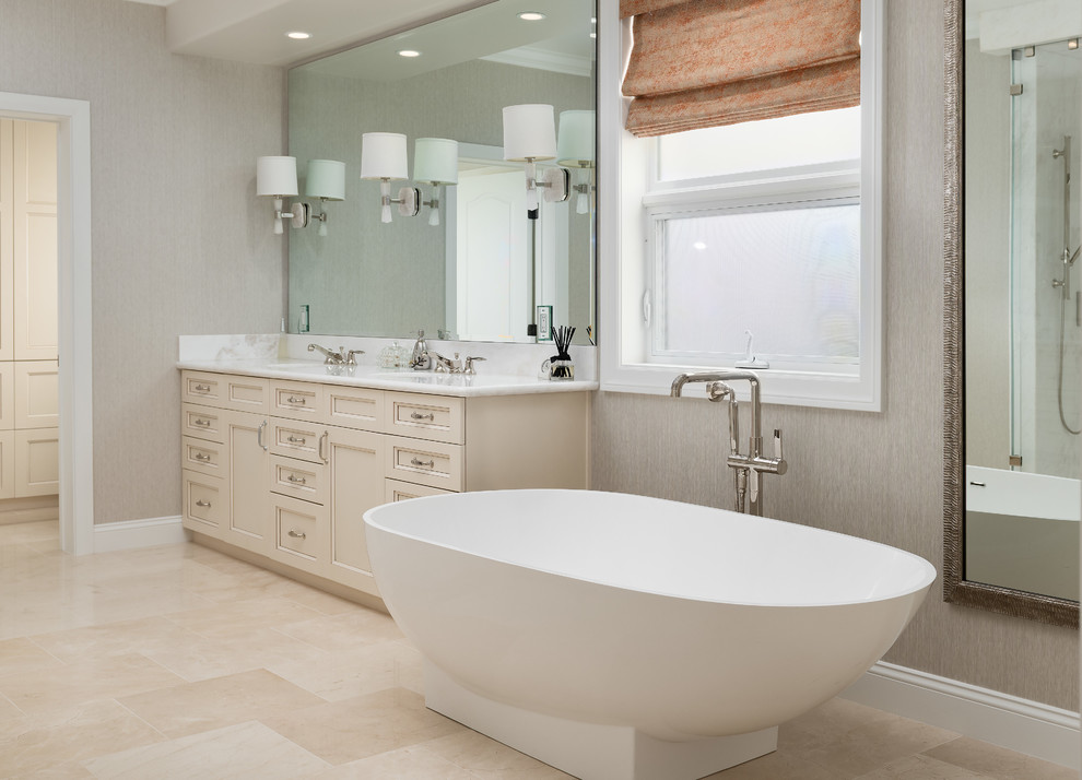 This is an example of a transitional master bathroom in Orange County with recessed-panel cabinets, white cabinets, a freestanding tub, an alcove shower, an undermount sink, beige floor, a hinged shower door and white benchtops.