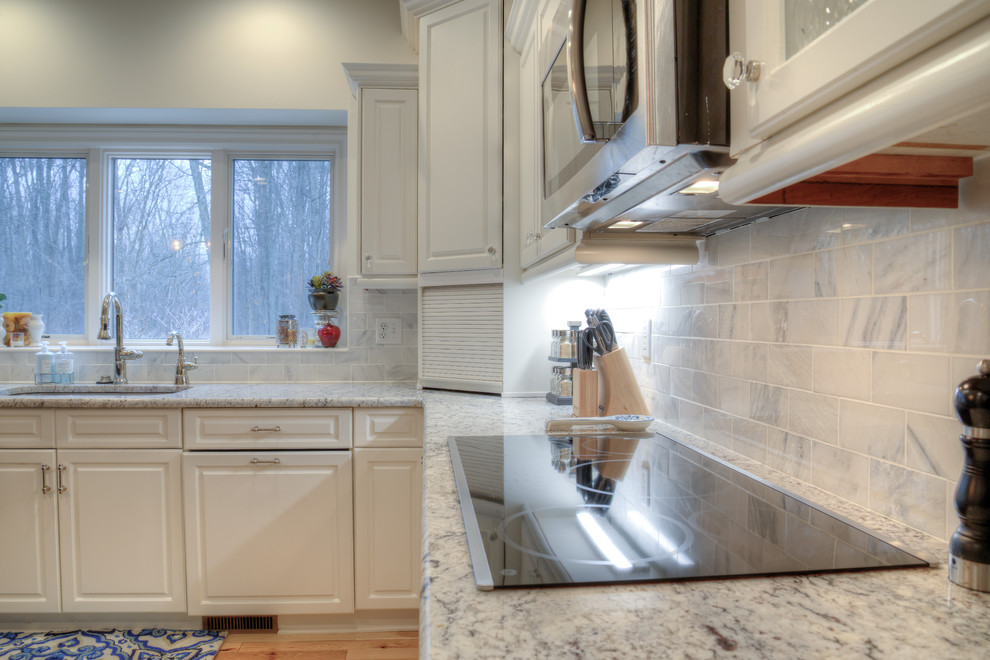 Inspiration for a mid-sized transitional l-shaped separate kitchen in Detroit with an undermount sink, raised-panel cabinets, white cabinets, granite benchtops, grey splashback, stone tile splashback, stainless steel appliances, light hardwood floors and with island.