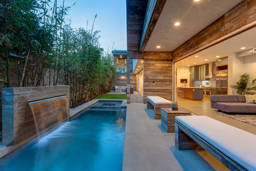 Inspiration for a mid-sized contemporary backyard rectangular lap pool in Los Angeles with concrete slab and a water feature.