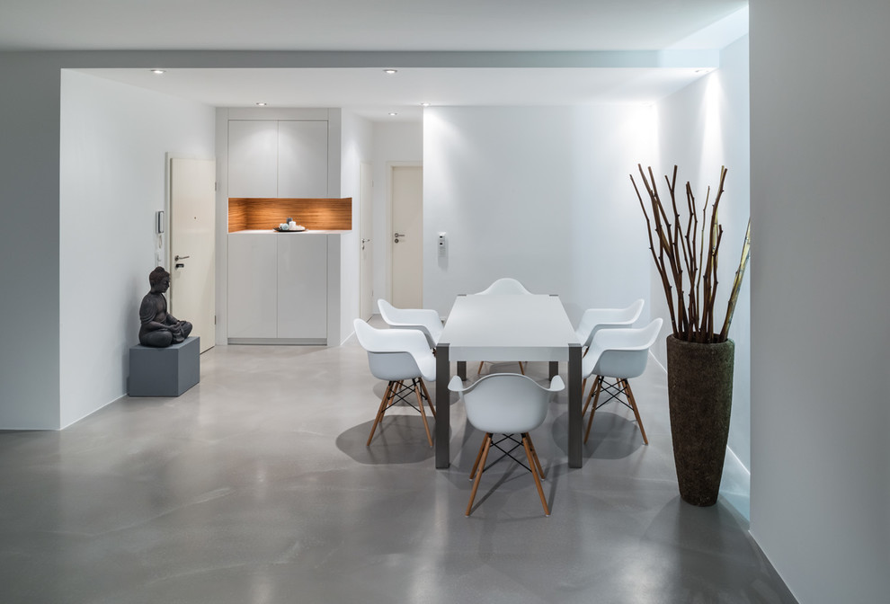 This is an example of a contemporary dining room in Frankfurt with white walls and concrete floors.