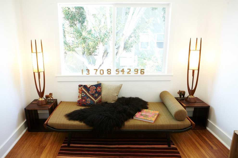 Eclectic bedroom in Los Angeles with white walls and medium hardwood floors.
