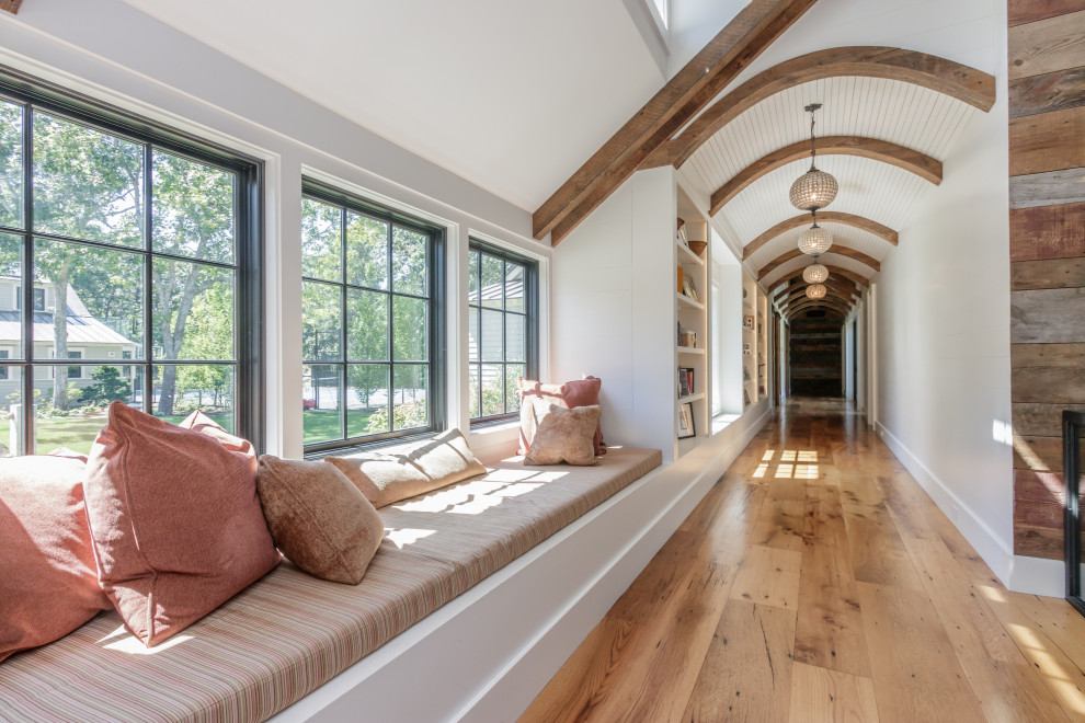Example of a cottage chic medium tone wood floor, brown floor, exposed beam and shiplap wall hallway design in Boston with white walls