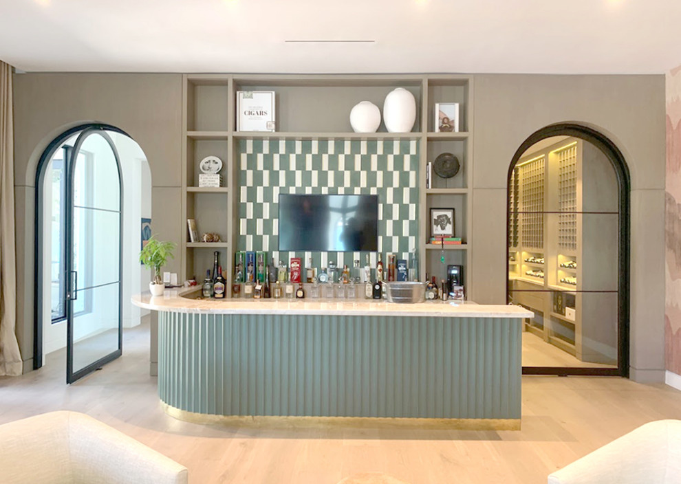 This is an example of an expansive contemporary single-wall seated home bar in Miami with an integrated sink, distressed cabinets, marble benchtops, multi-coloured splashback, porcelain splashback, light hardwood floors, brown floor and beige benchtop.