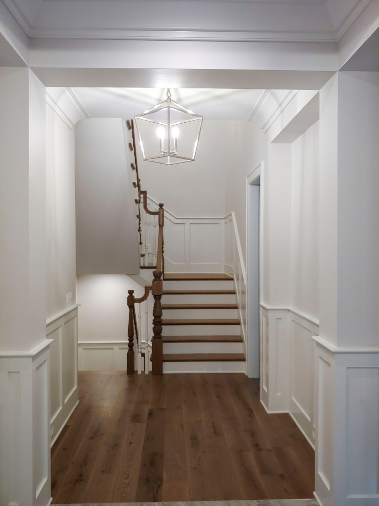 Medium sized traditional wood u-shaped wood railing staircase in DC Metro with painted wood risers and wainscoting.