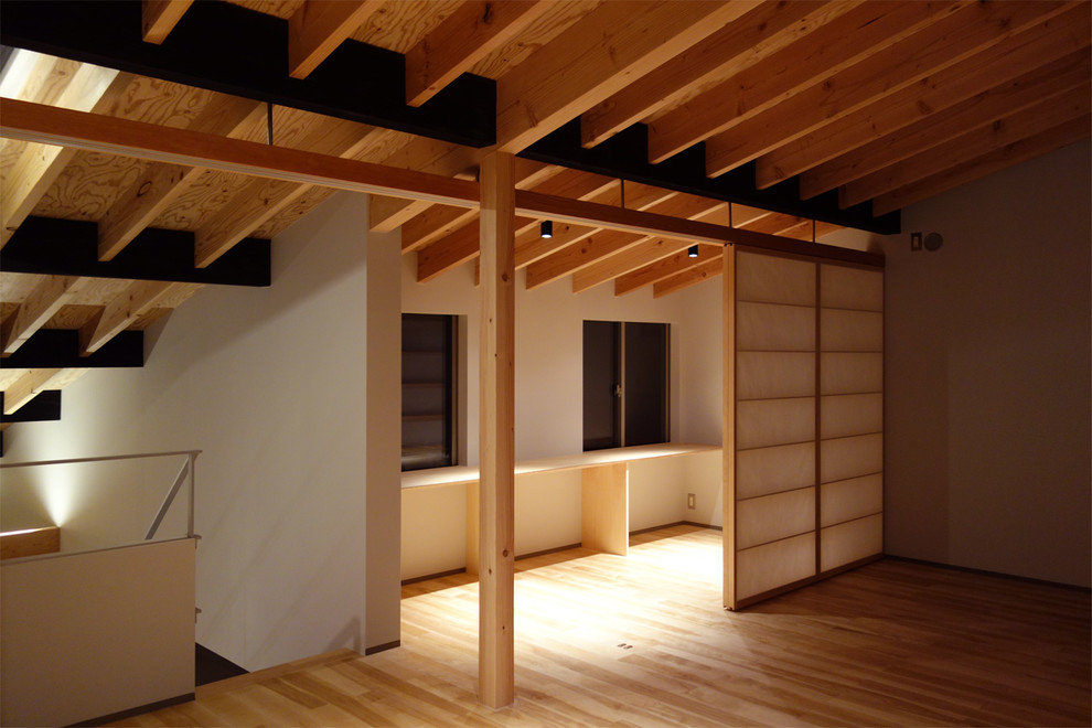 This is an example of a modern master bedroom in Tokyo with grey walls and light hardwood floors.